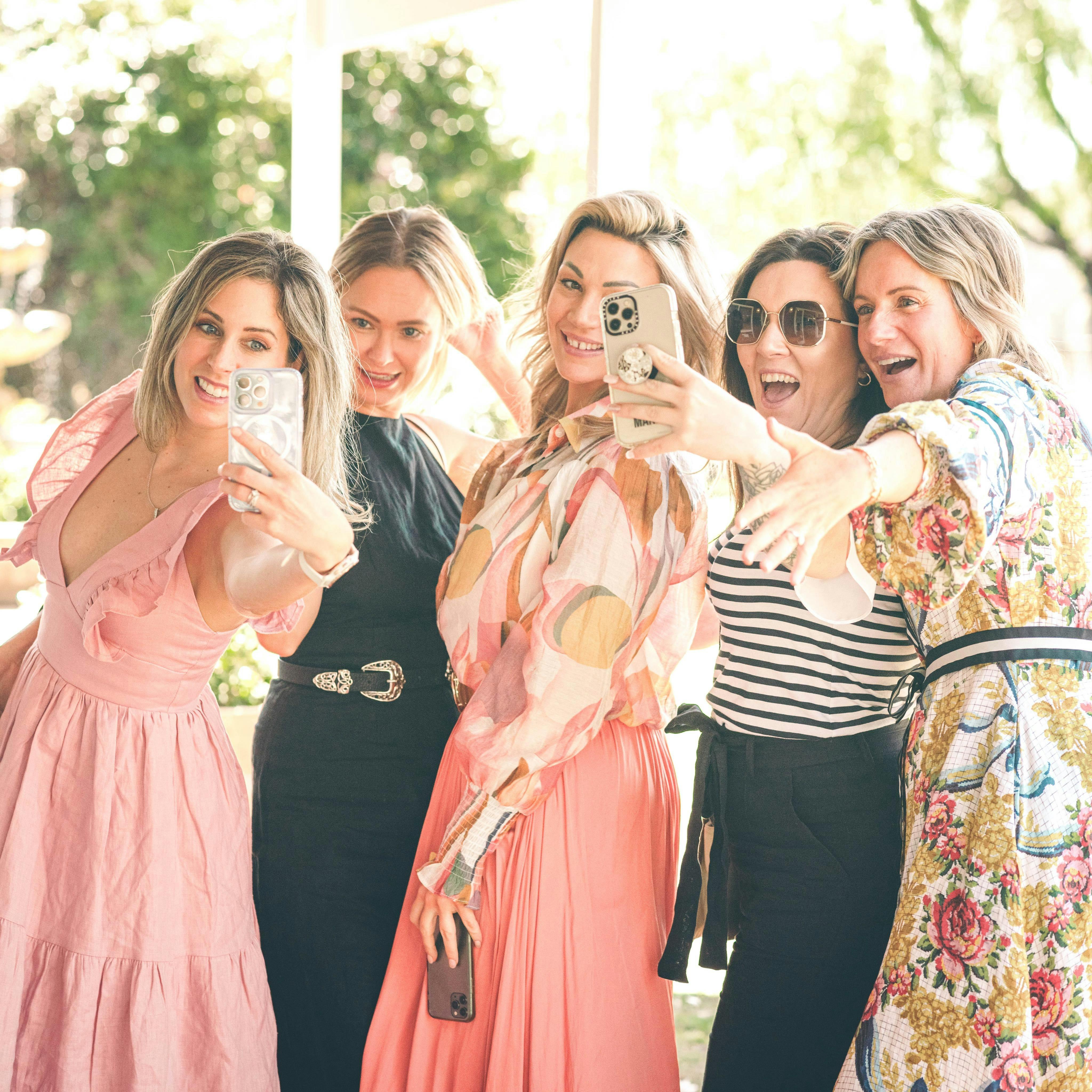 5 women taking selfies together with big grins on their faces