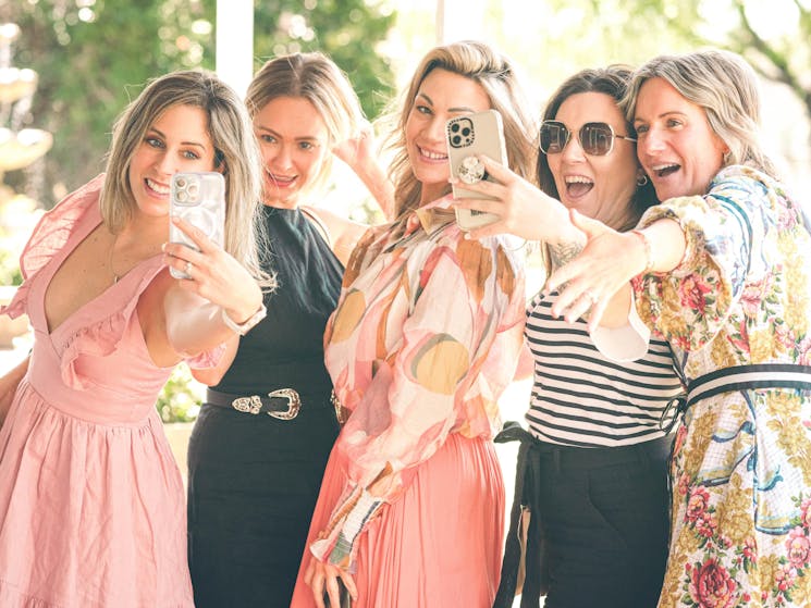 5 women taking selfies together with big grins on their faces
