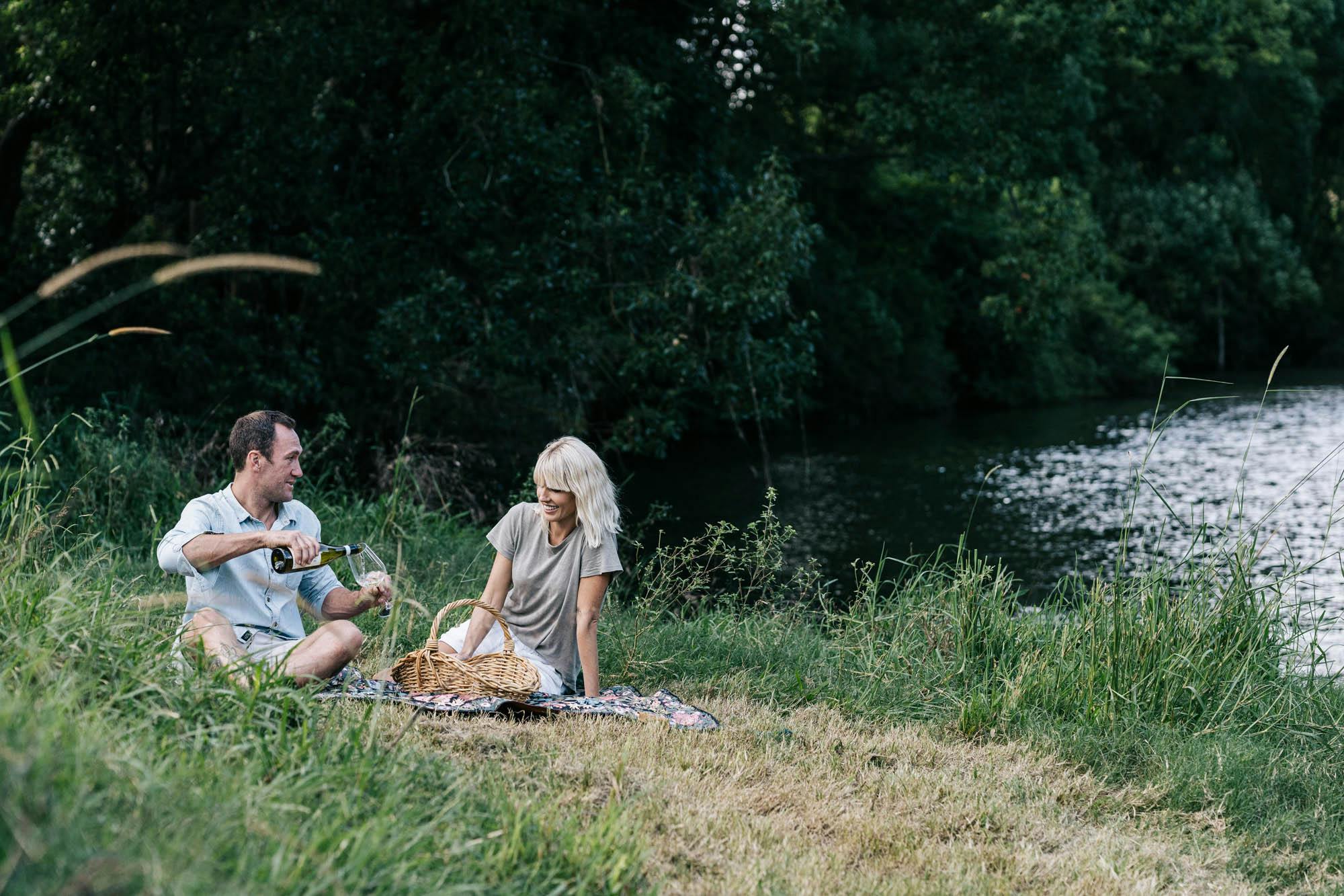 A couple picnicing on the banks of the Wilson River on a Wandering Folk picnic rug