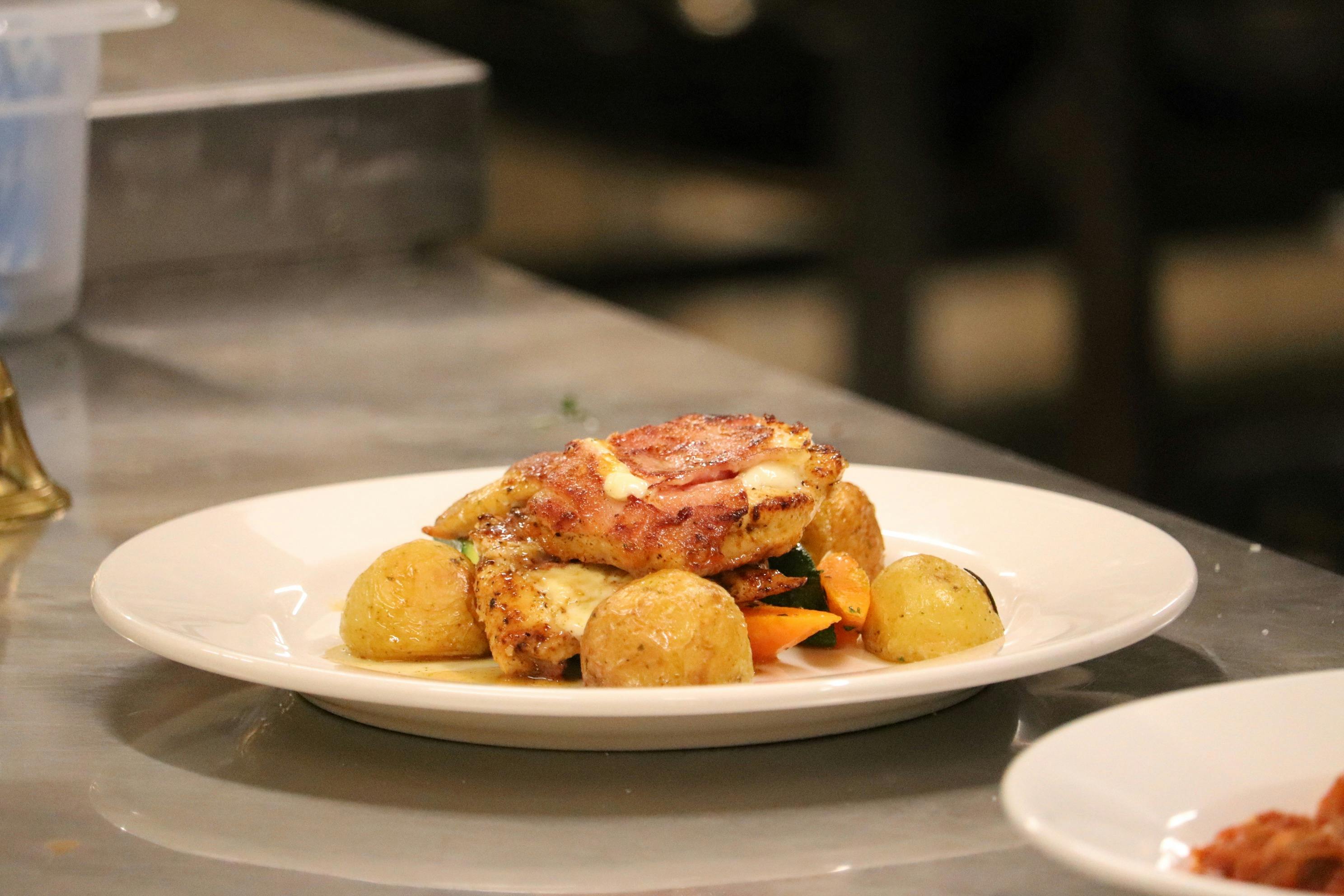 Grilled chicken with melted cheese, baby potatoes, and mixed vegetables on a plate