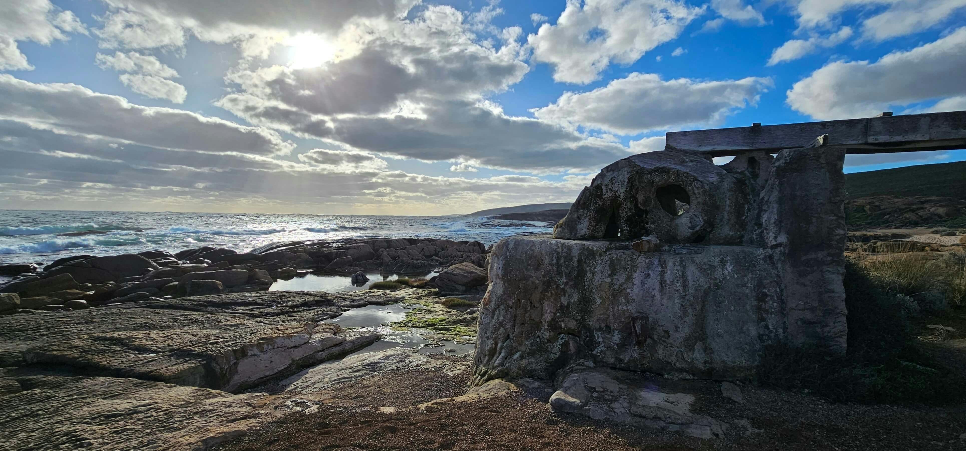 Rocky beach landscape with still water pooling in the rock spaces, sunny cloudy sky