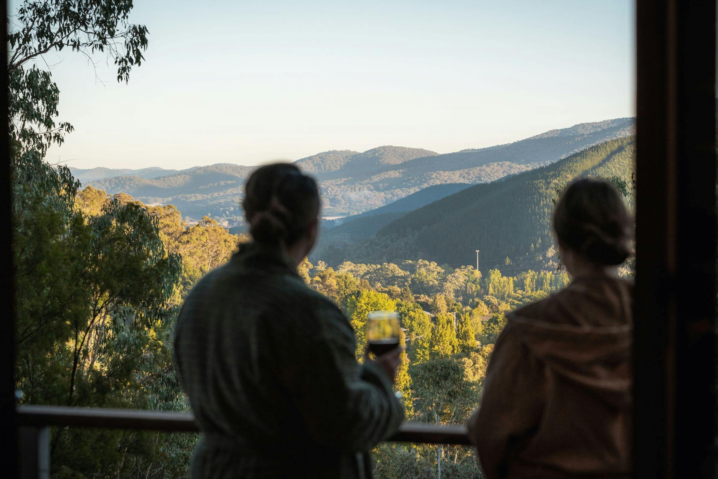 Couple on a private treehouse balcony with views over the Ovens Valley near Bright, Victoria