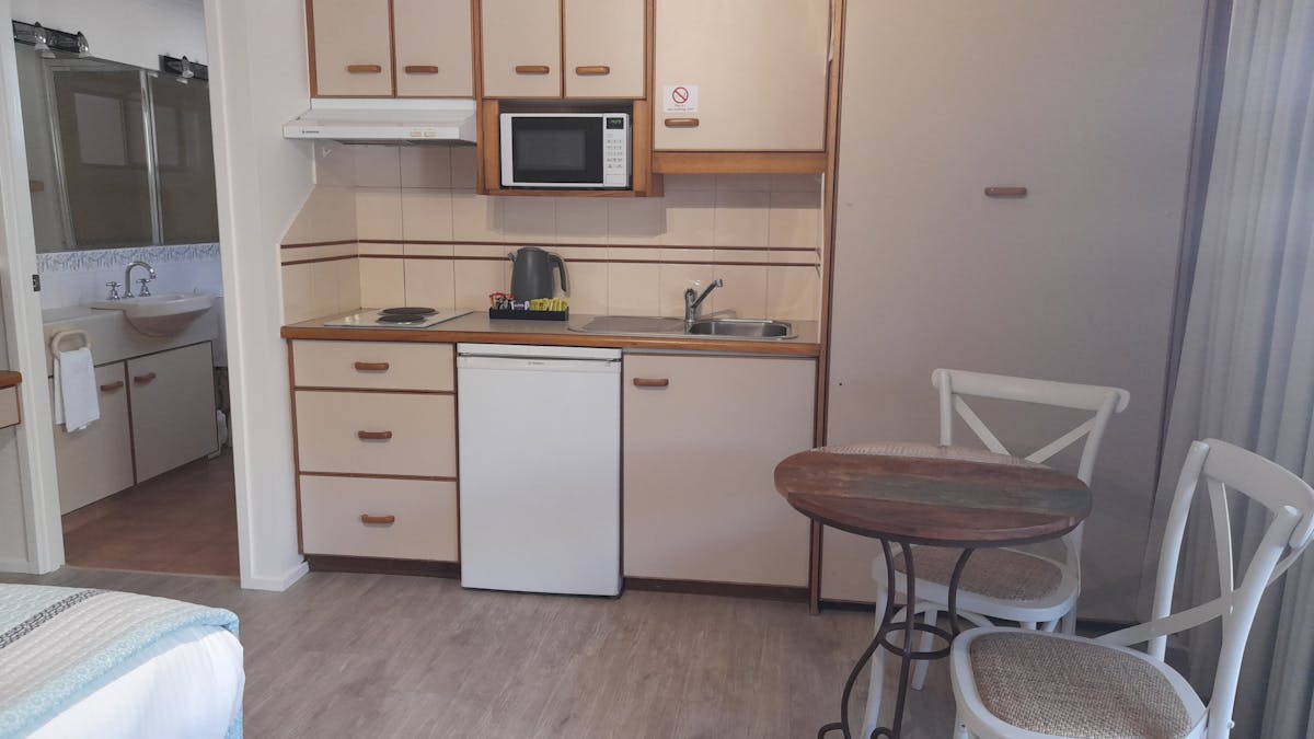 Kitchenette in a studio apartment contains a small fridge, cooktop, microwave, toaster and kettle