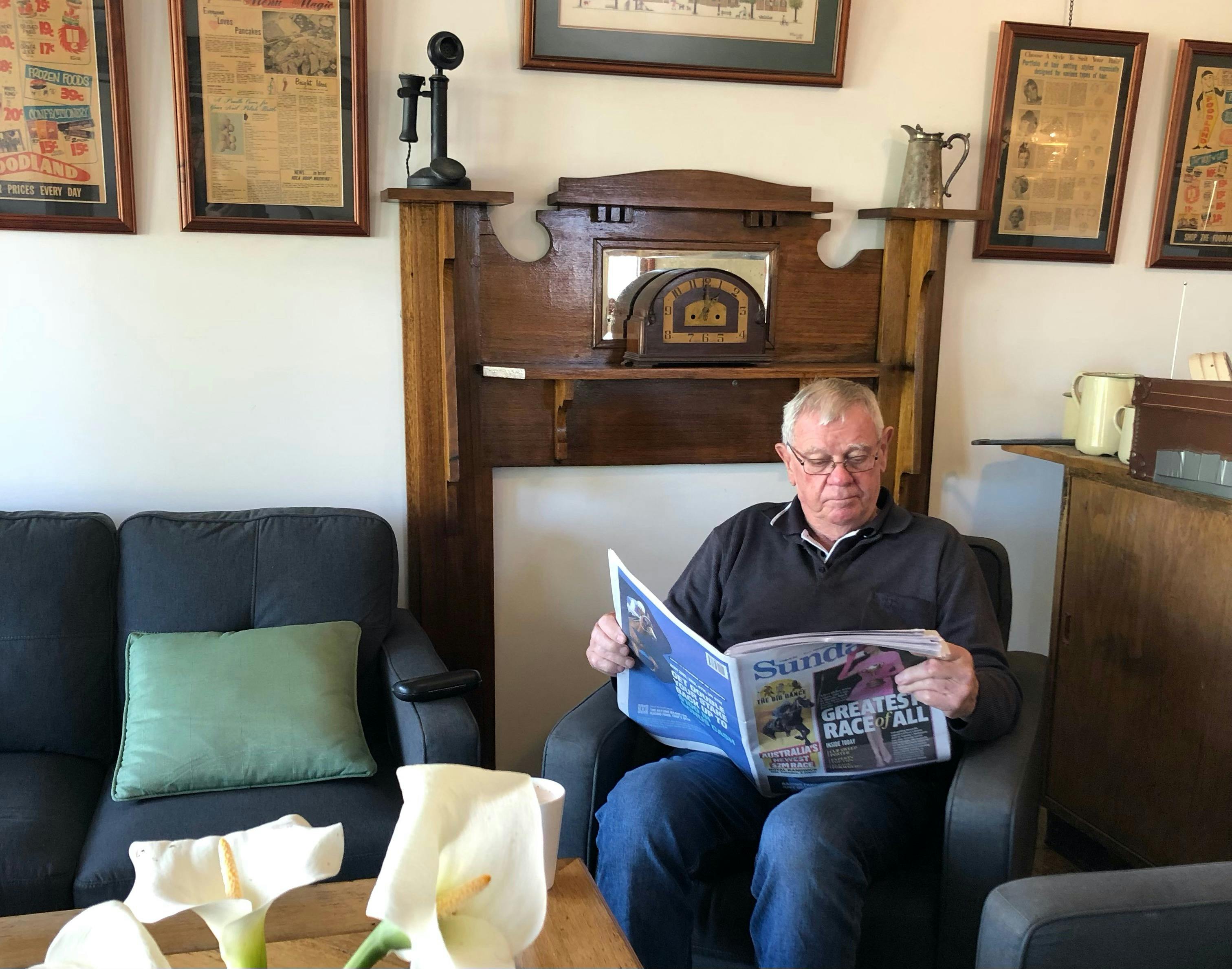 Man reading a newspaper on an easy chair.