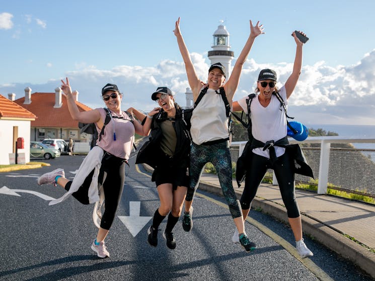 Four women jump in front of the Cape Byron Lighthouse