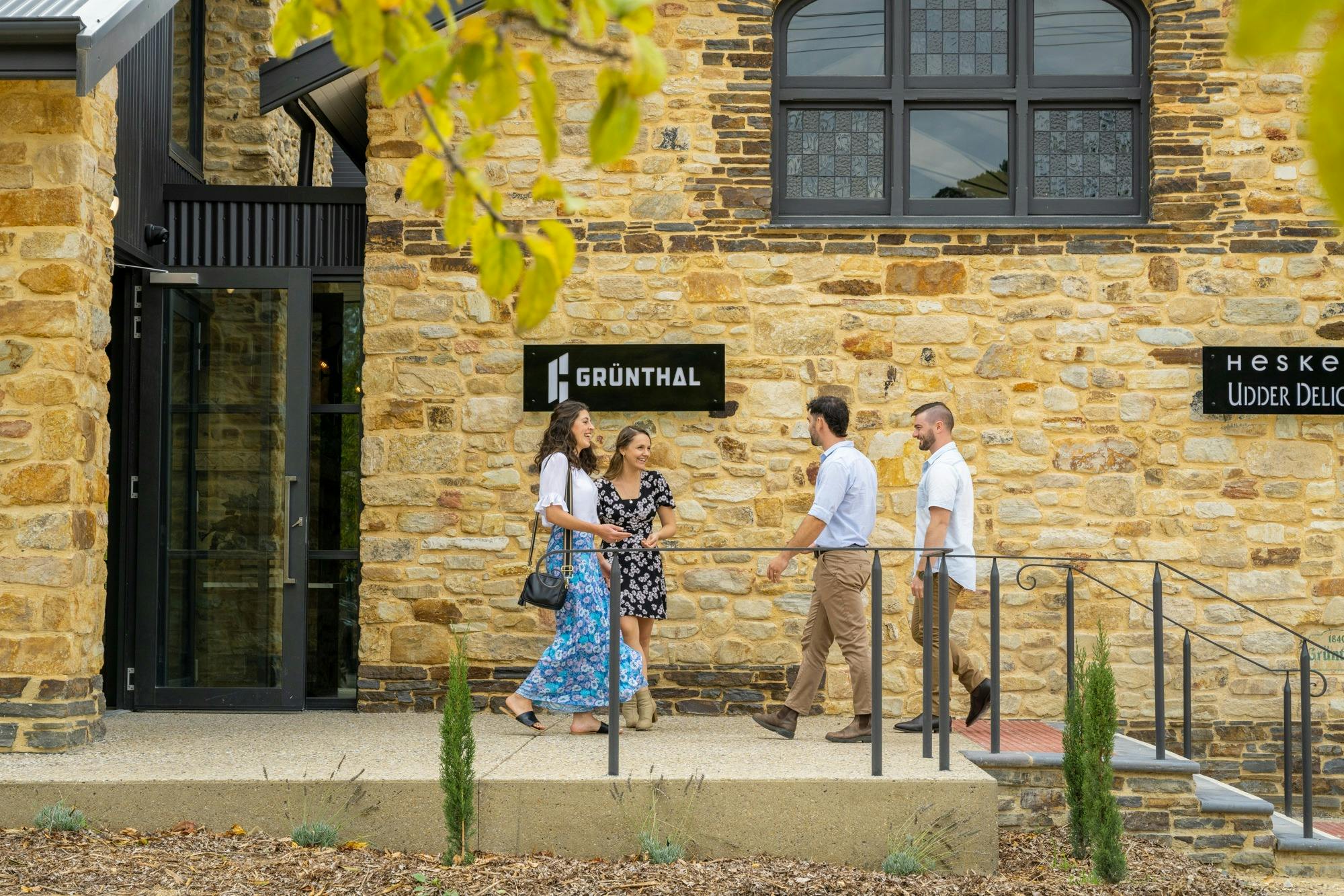 four people standing outside stone building
