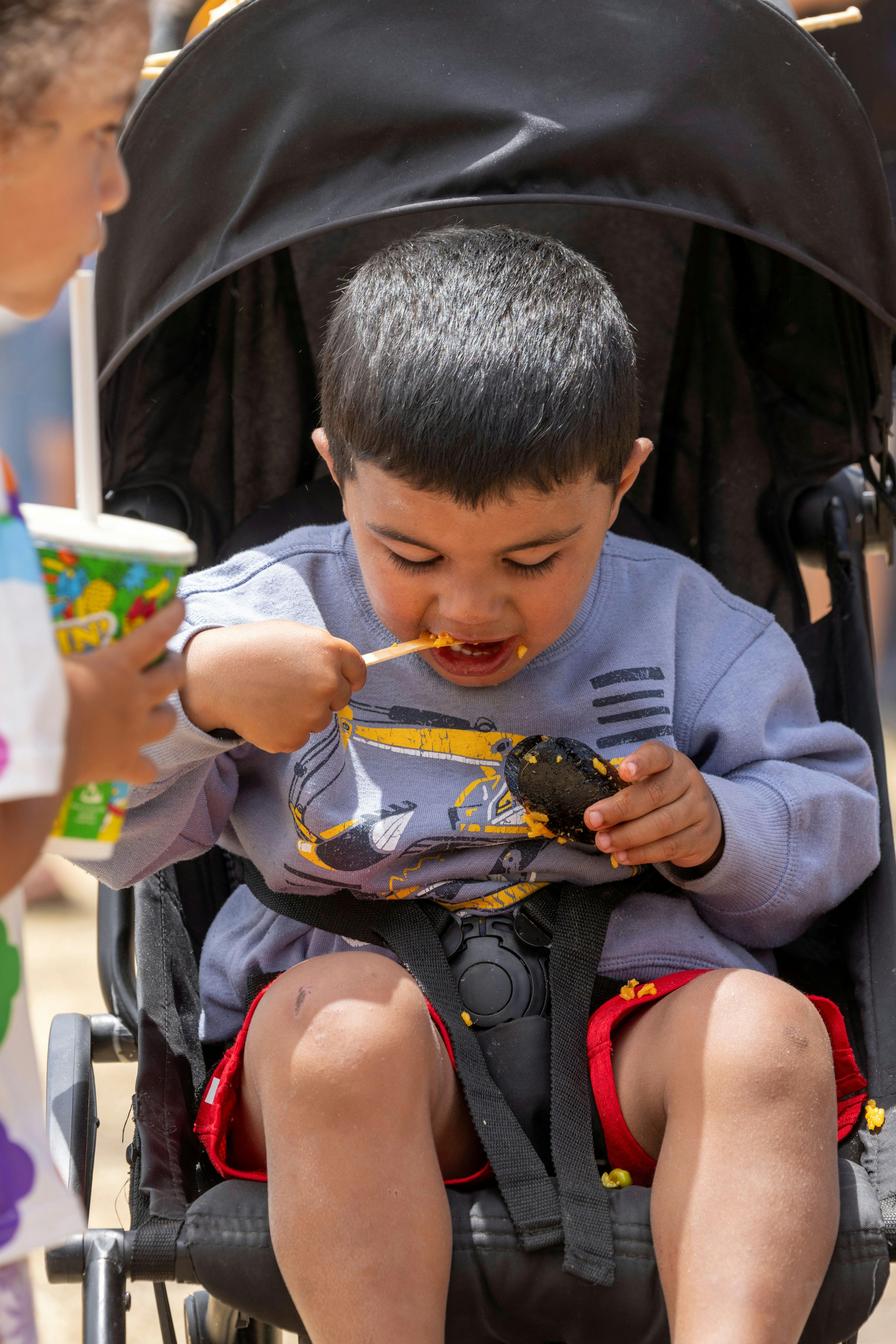 Little boy sitting in a pram and eating mussels