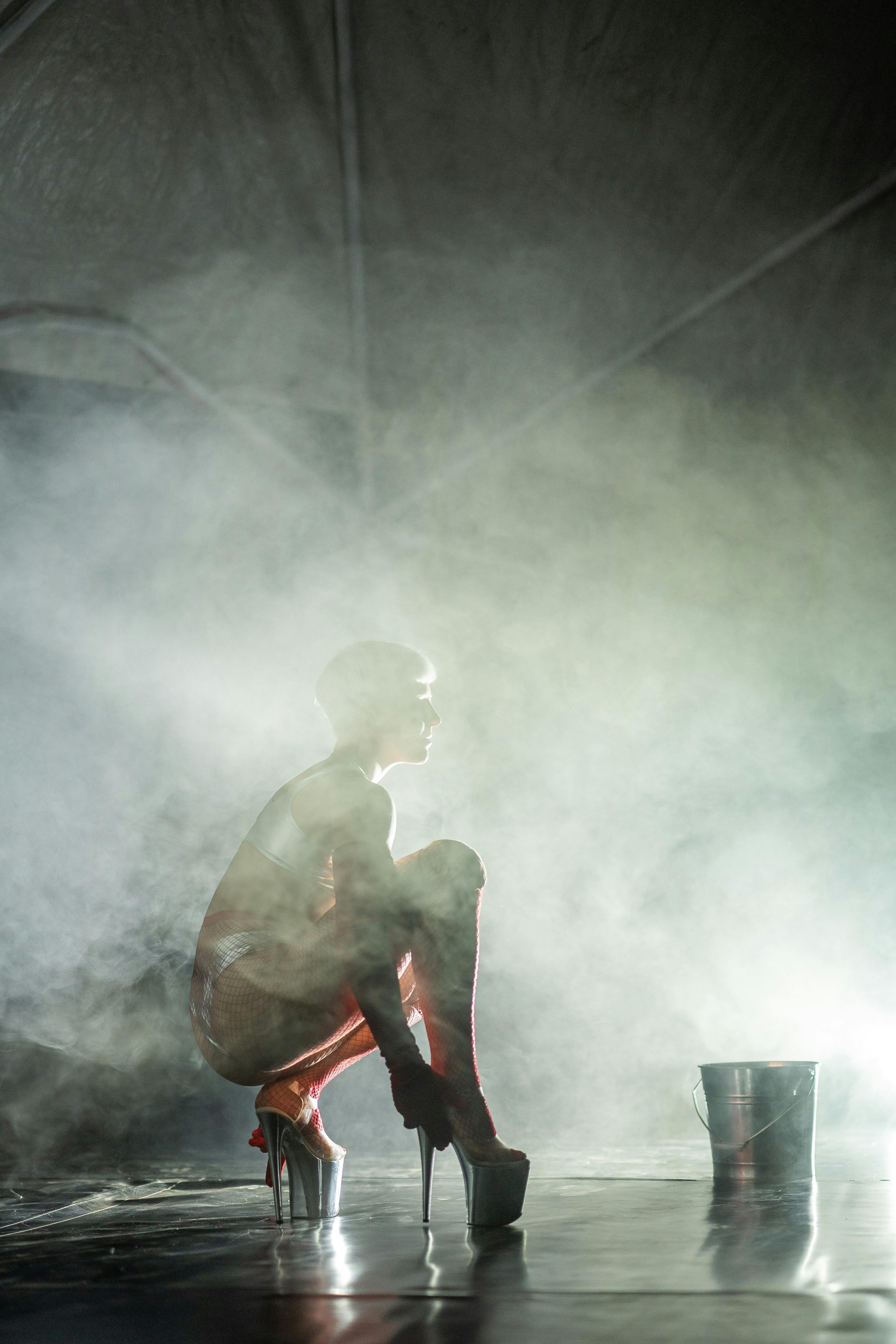 Dancer on stage amidst smoke with large heels and bucket