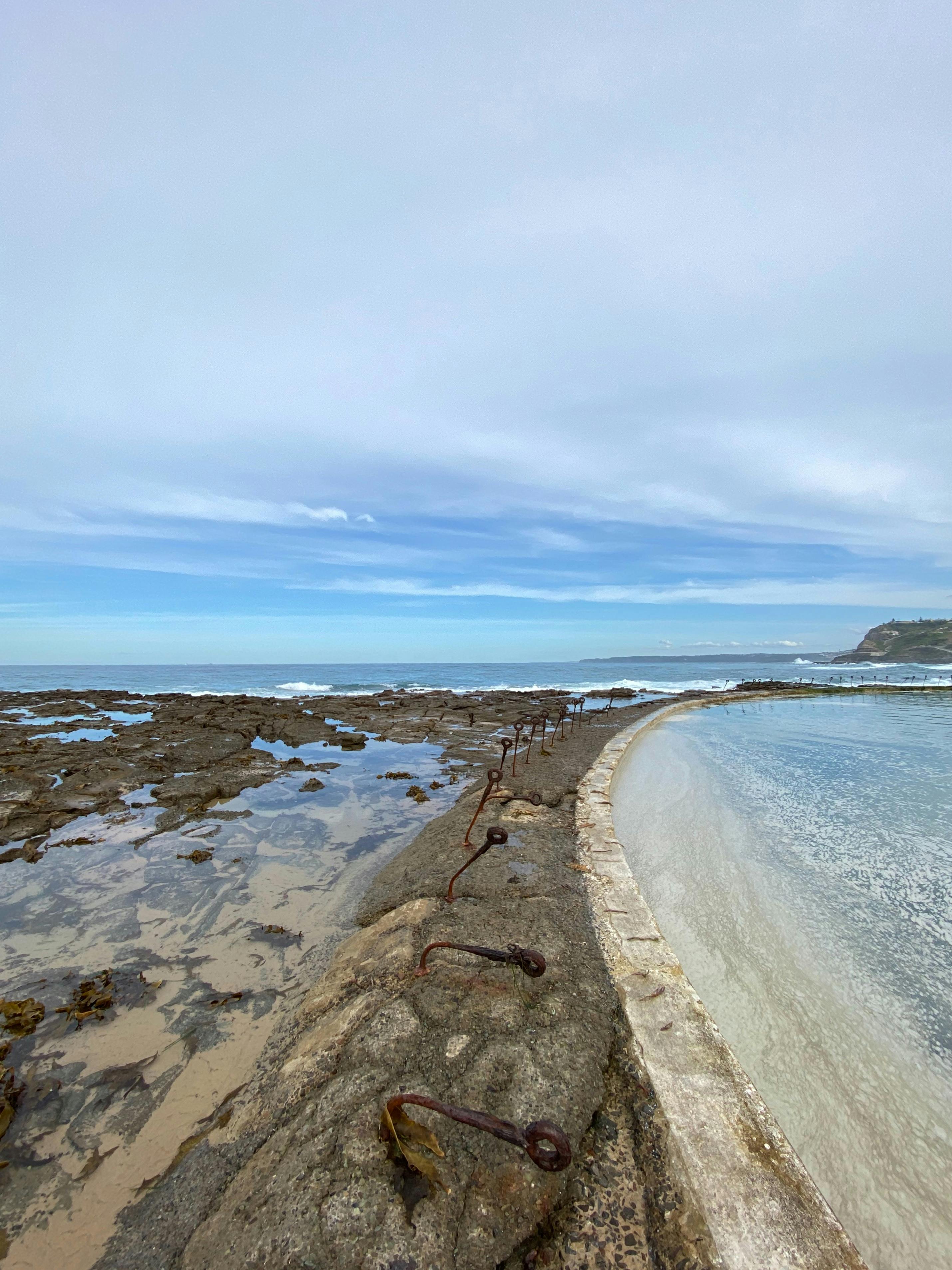 View of a rounded concrete wall at the world pool, next to the ocean