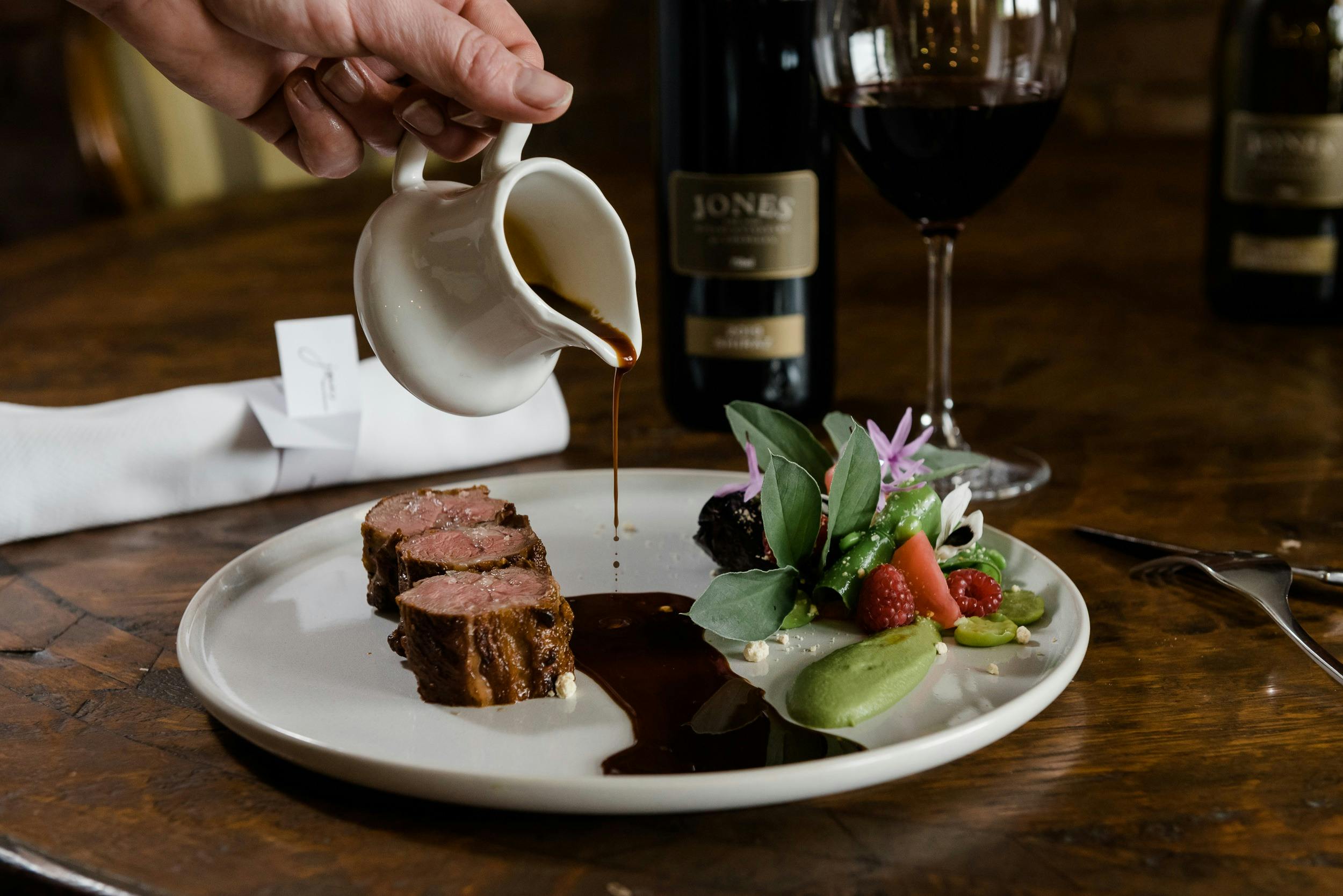 Sauce being poured onto medalions of lamb