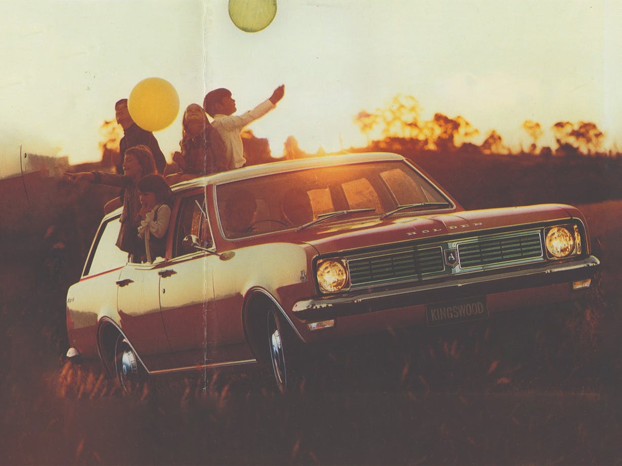A Holden Kingswood car parked  on a grassy field at sunset with children hanging out of the windows
