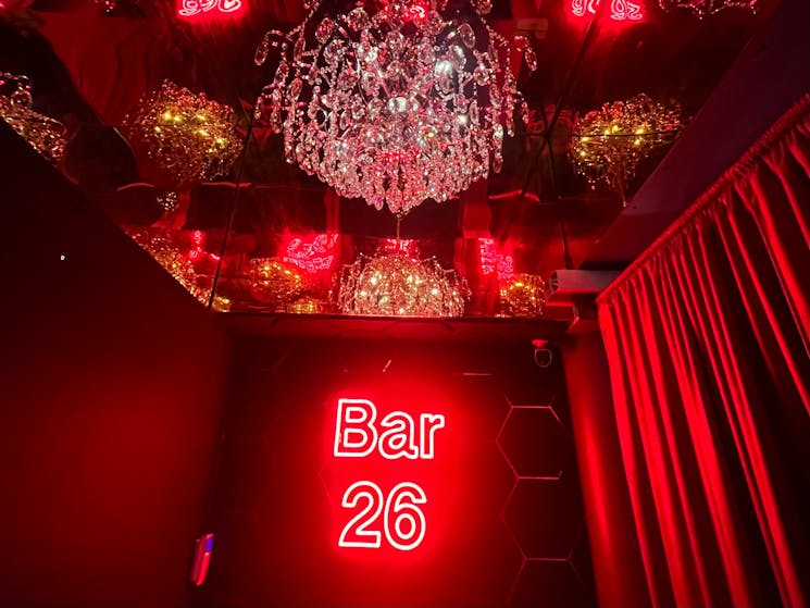 Entering Bar 26, you will be greated with our red neon, gold mirrored ceiling and chandelier