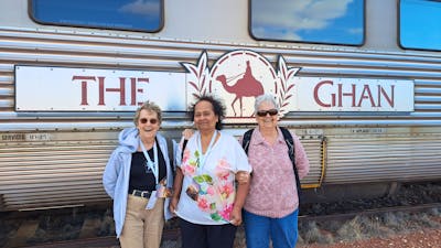 three senior ladies infront of a train carriage and the ghan sign