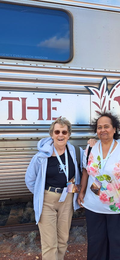 three senior ladies infront of a train carriage and the ghan sign