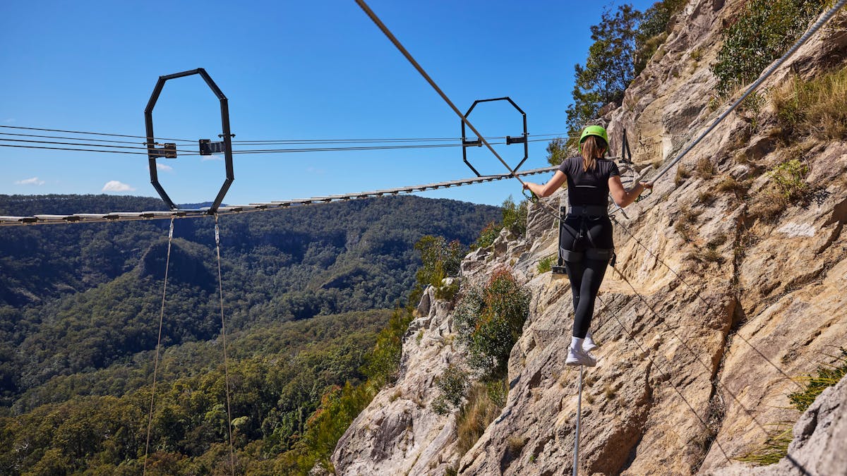 Woman walking across Via Ferrata at Happitat Adventure Park