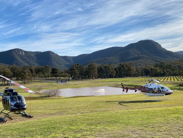 Two helicopters in the countryside of the Hunter Valley with the Broke Back mountain range