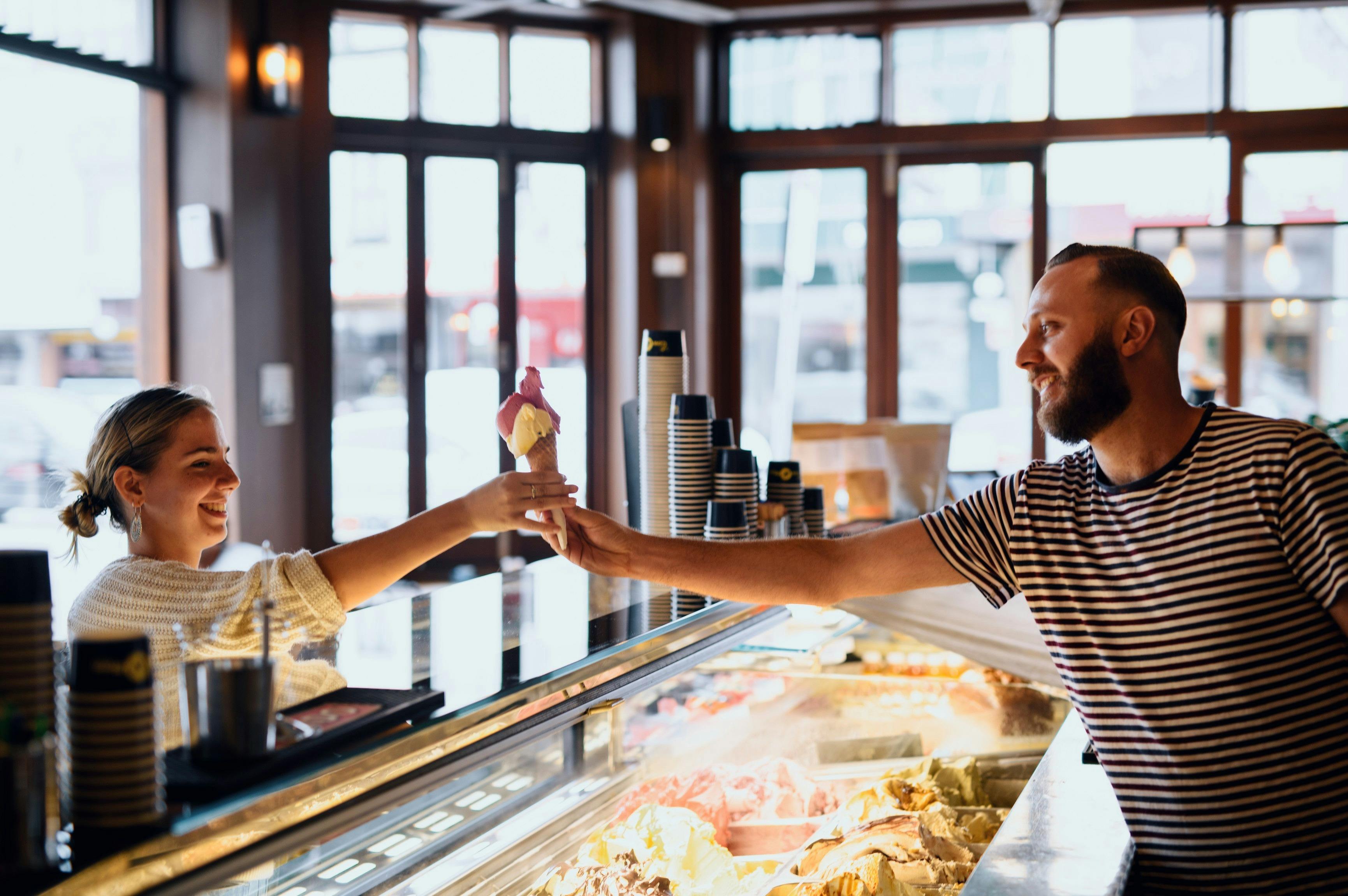 Man scooping gelato for a customer at Cow and The Moon artisan gelato store on Enmore Road, Enmore