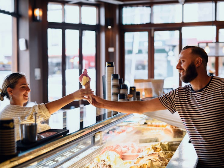 Man scooping gelato for a customer at Cow and The Moon artisan gelato store on Enmore Road, Enmore