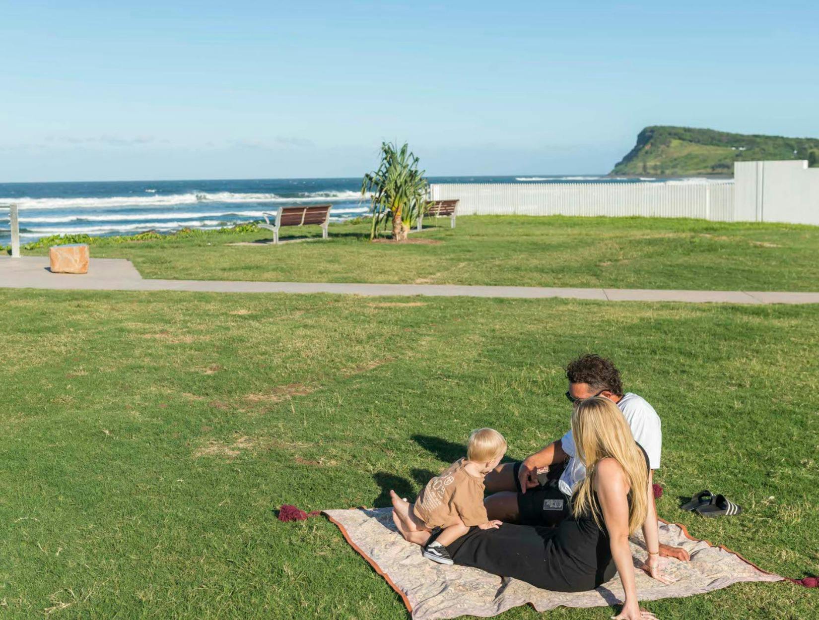 Couple and child sitting on a rug in Lennox Park Lennox Head nsw