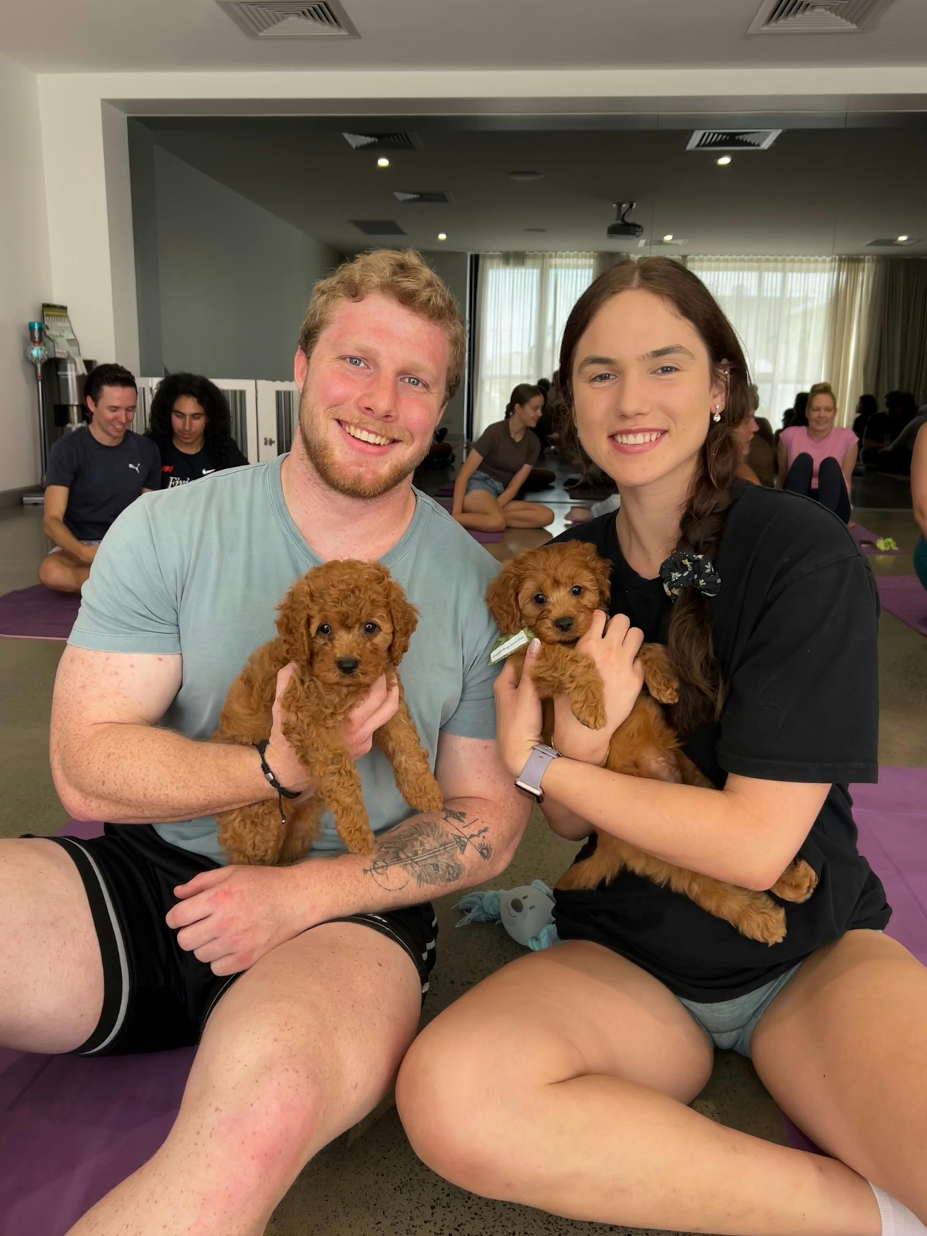 Two participants share puppy cuddles at a Yoga Paws puppy yoga session in Brisbane.