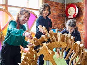 Adult and 2 primary school aged children building a wooden dinosaur