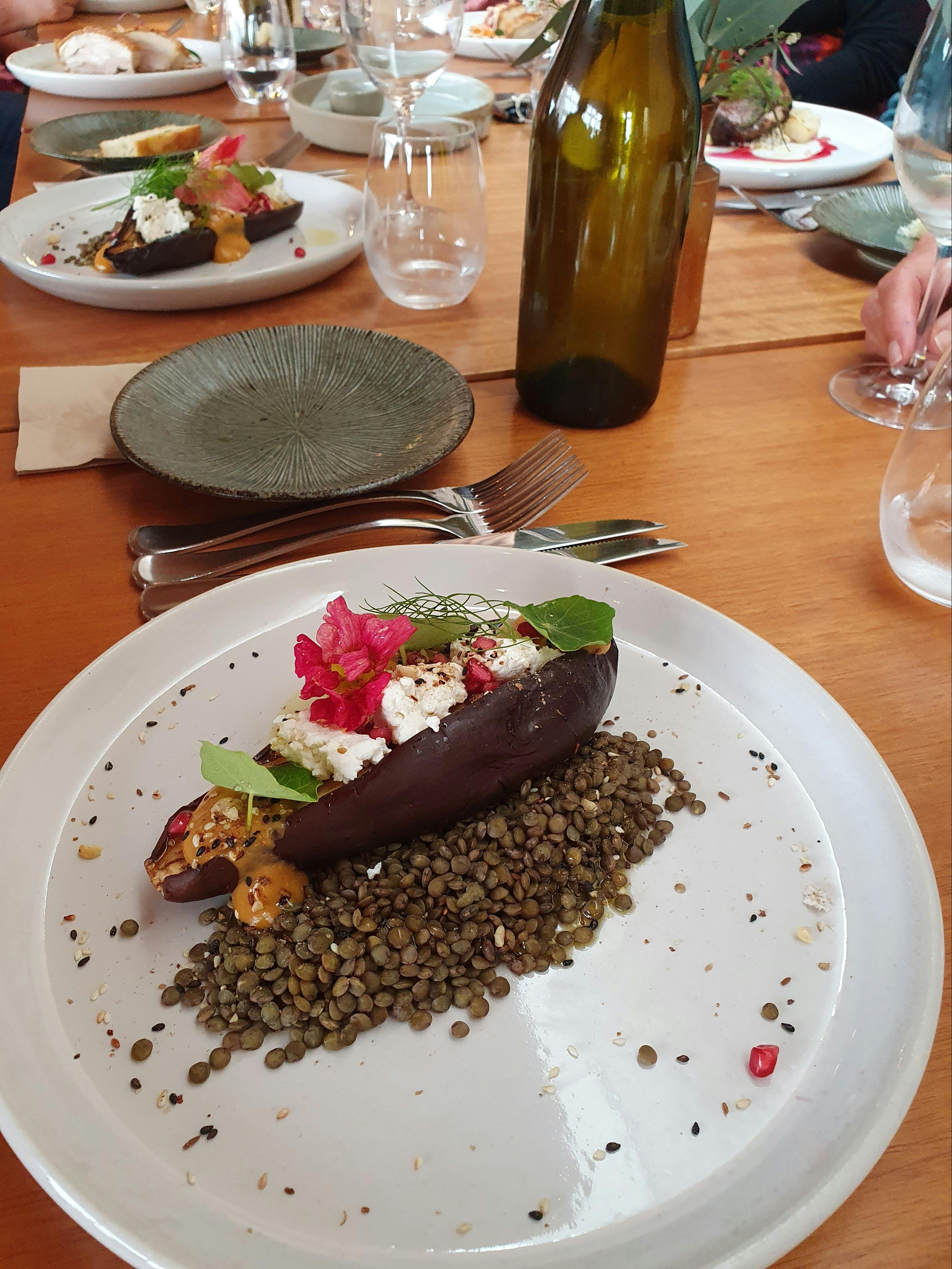 dinner plate with meal on a table with wine and glasses