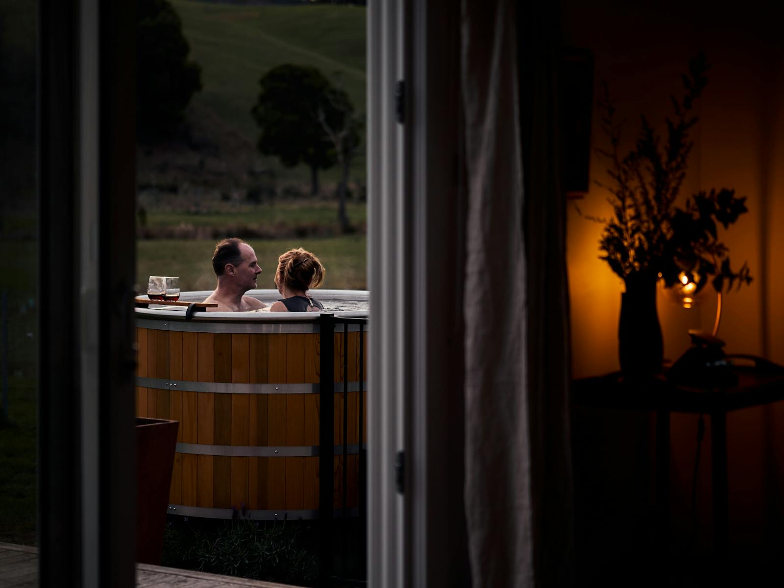 Looking from inside out to a man and woman sitting in a hot tub outside