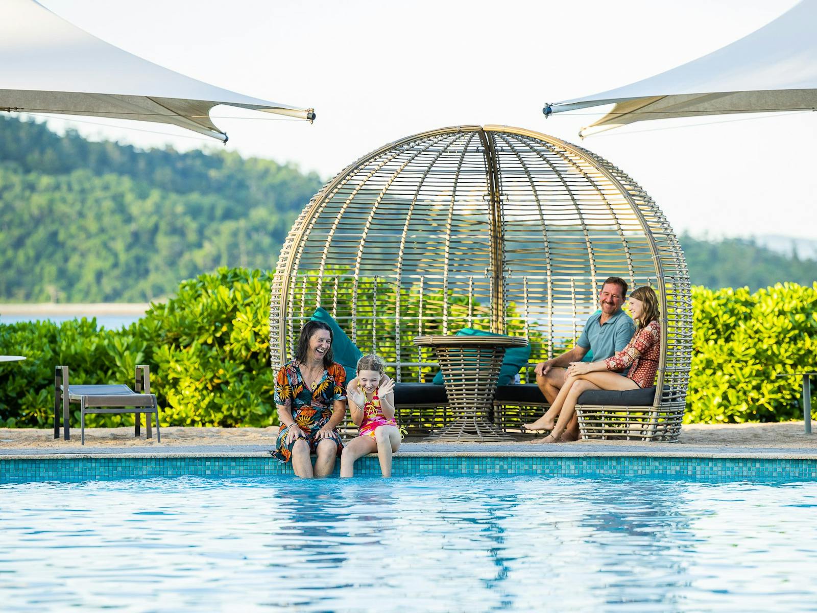 Young family of four smiling in the main pool area on Daydream Island.