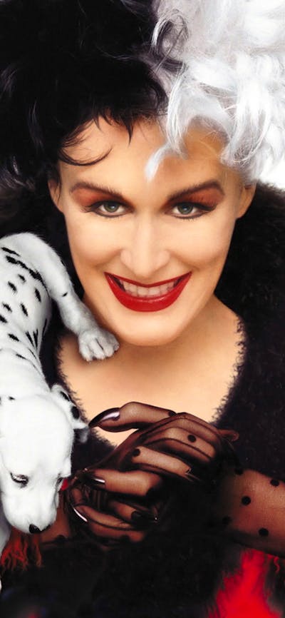 Woman with half black and half white hair with threedalmatian  puppies climbing over her