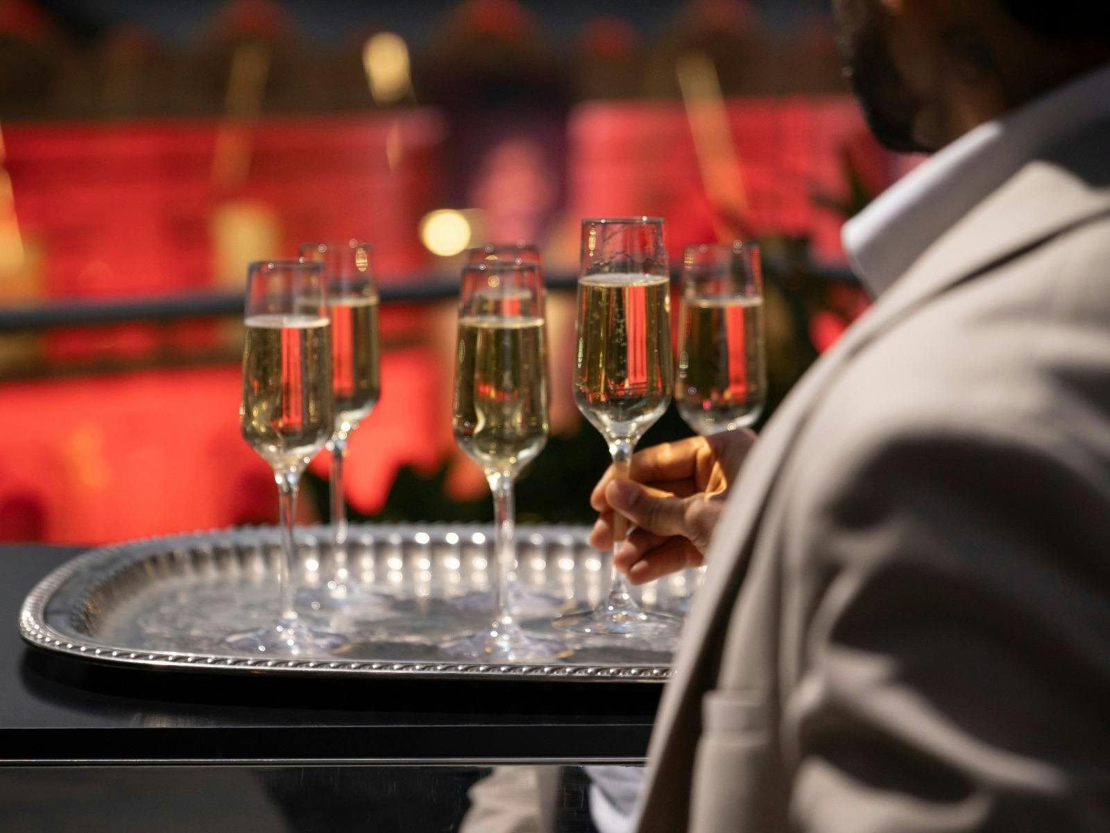 Tray of champagne glasses and a male taking a glass off the tray.