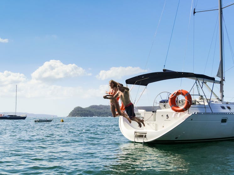 Man and lady jumping off a Taylor Made Escapes yacht in beautiful Pittwater