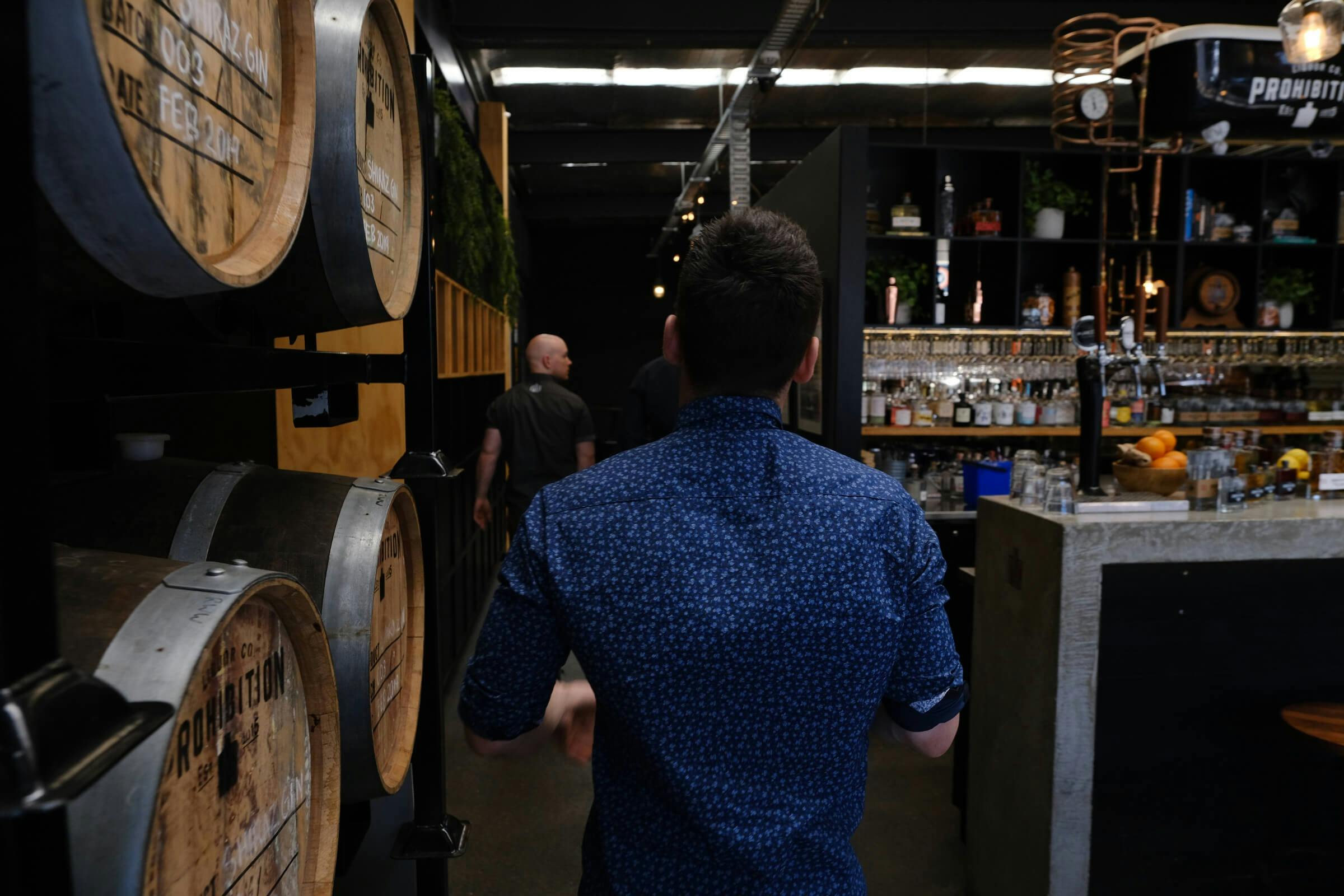 Man on tour walking through barrel room of distillery