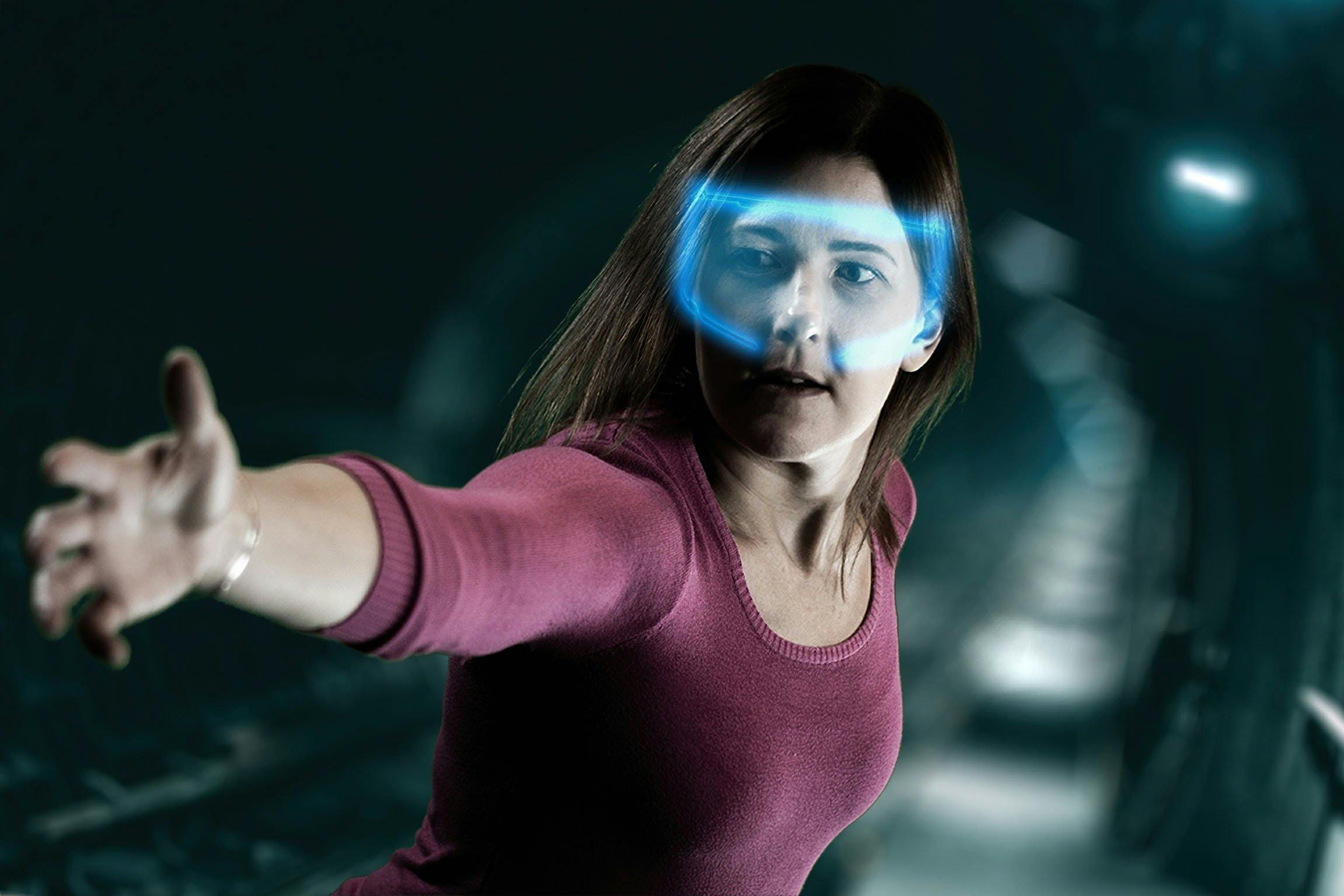 Lady with glowing VR headset reaching out to a camera in escape room