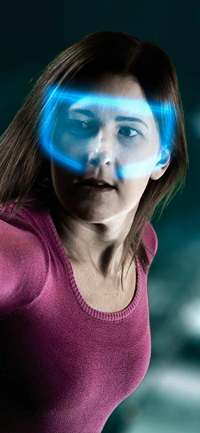 Lady with glowing VR headset reaching out to a camera in escape room