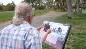 Back of man obstructing woman who has smartphone in front of sign