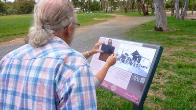 Back of man obstructing woman who has smartphone in front of sign