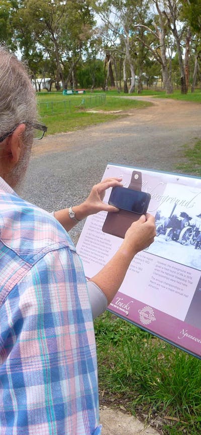 Back of man obstructing woman who has smartphone in front of sign