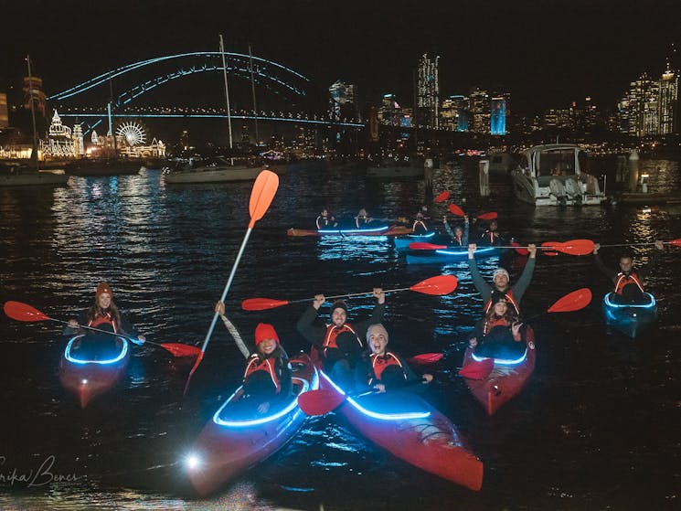 group of kayakers in custom lit kayaks in front of the iconic harbour