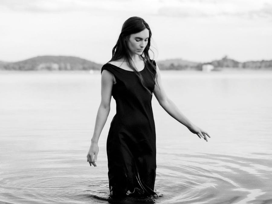 Lisa Mitchell stands knee deep in the ocean looking at the water