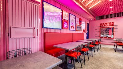 Bright-pink interior decorated with various props. Red booths. (Bad Bunny's interior)