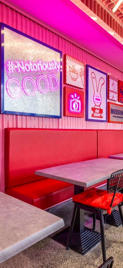 Bright-pink interior decorated with various props. Red booths. (Bad Bunny's interior)