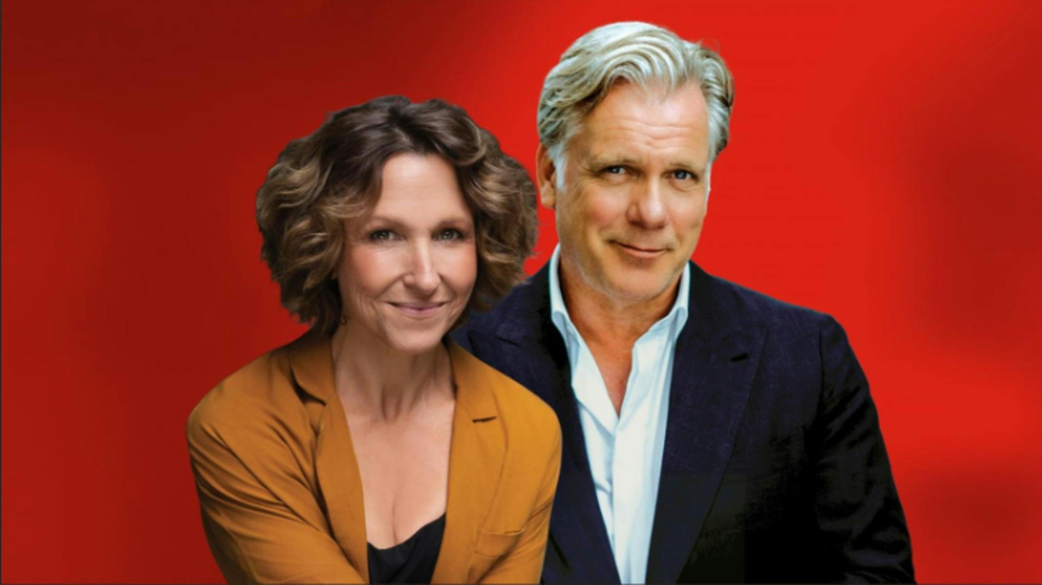 一位身穿橙色西装外套的女士和一位身穿海军蓝西装的男士在鲜艳的红色背景前合影。