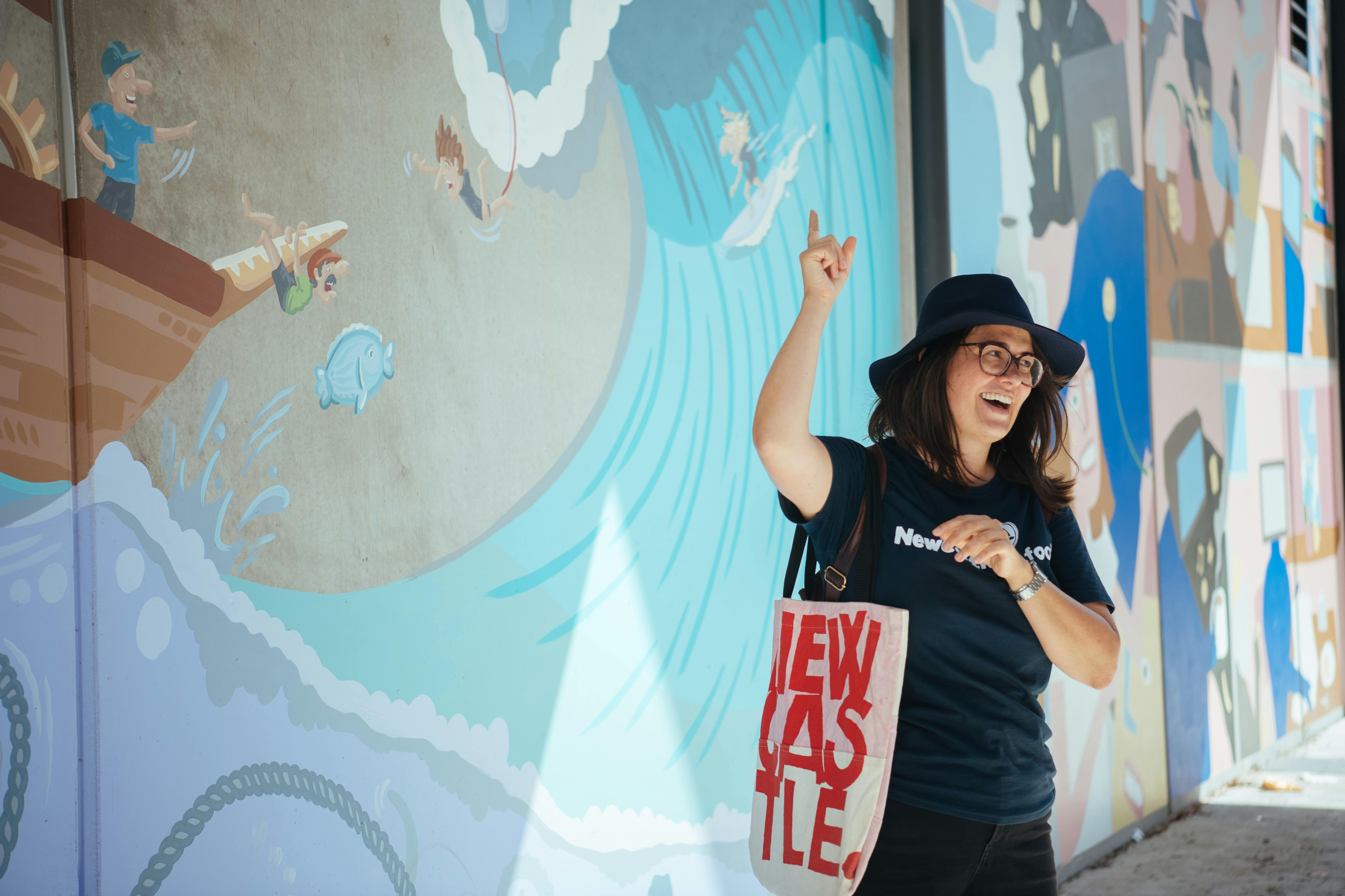 Newcastle Afoot guide talking in front of a large street art mural by Mitch Revs