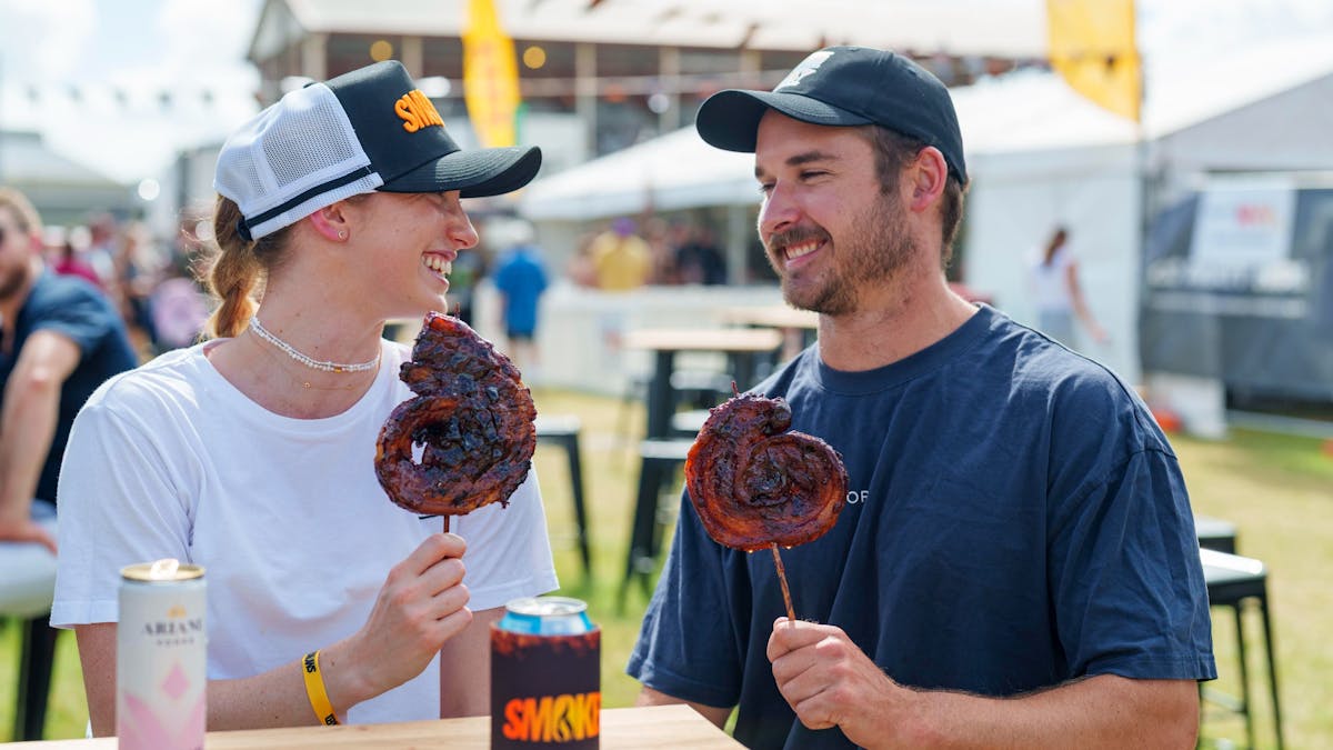 man and woman eating pork lollipops smiling