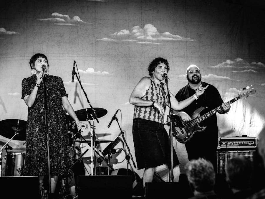 Stiff Gins perform on stage with a backdrop behind