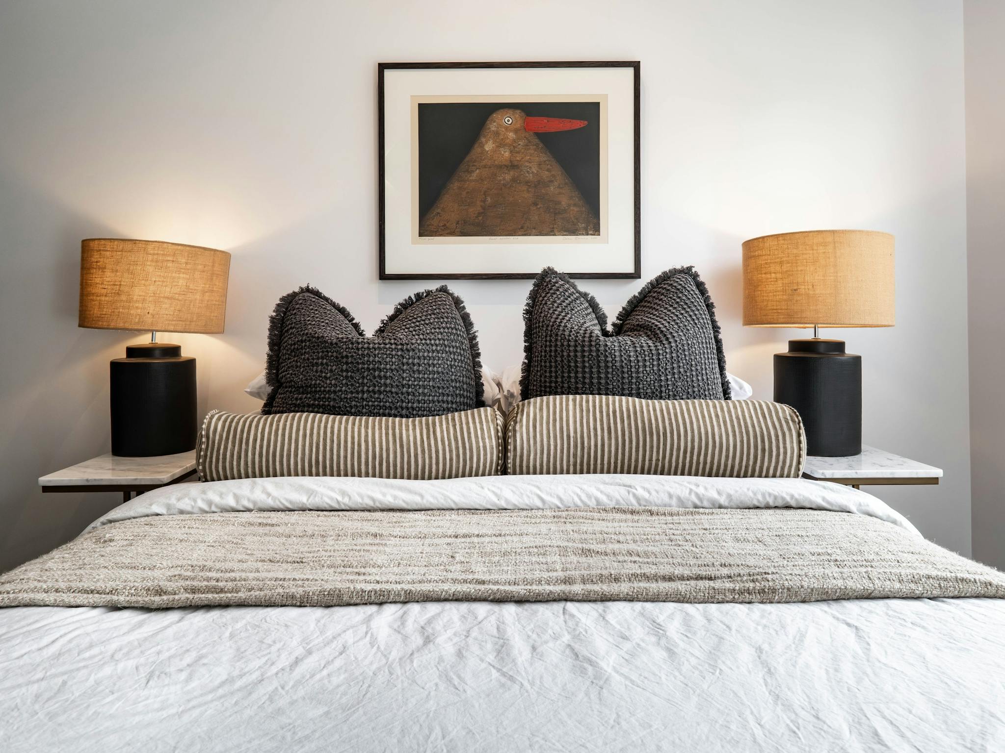 Olsen Penthouse bedroom with bed, pillows and cushions, bedside lamps and painting on the wall