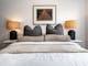 Olsen Penthouse bedroom with bed, pillows and cushions, bedside lamps and painting on the wall