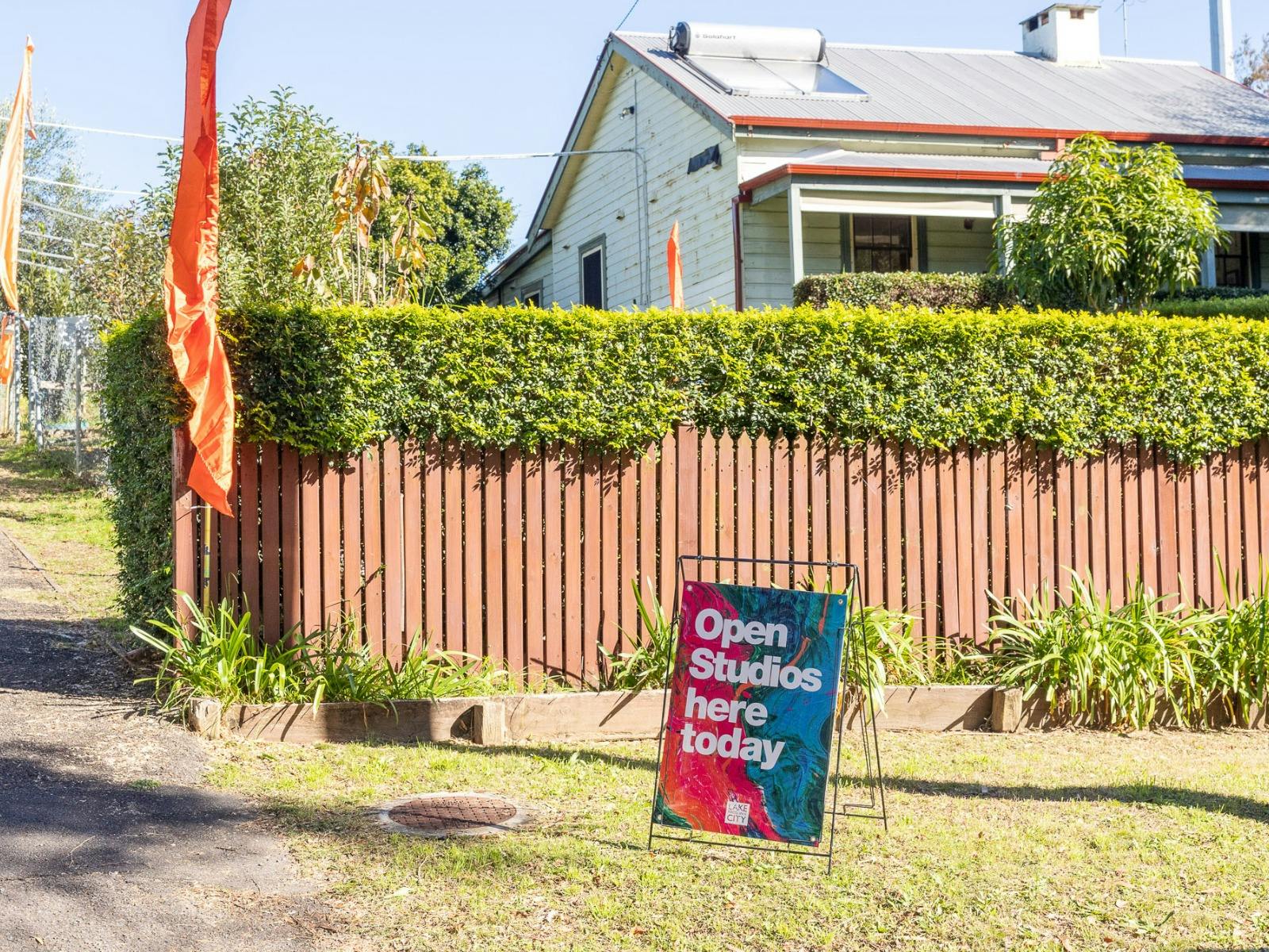 Street view of a house and fence with a sign in front reading 'Open studios here today'