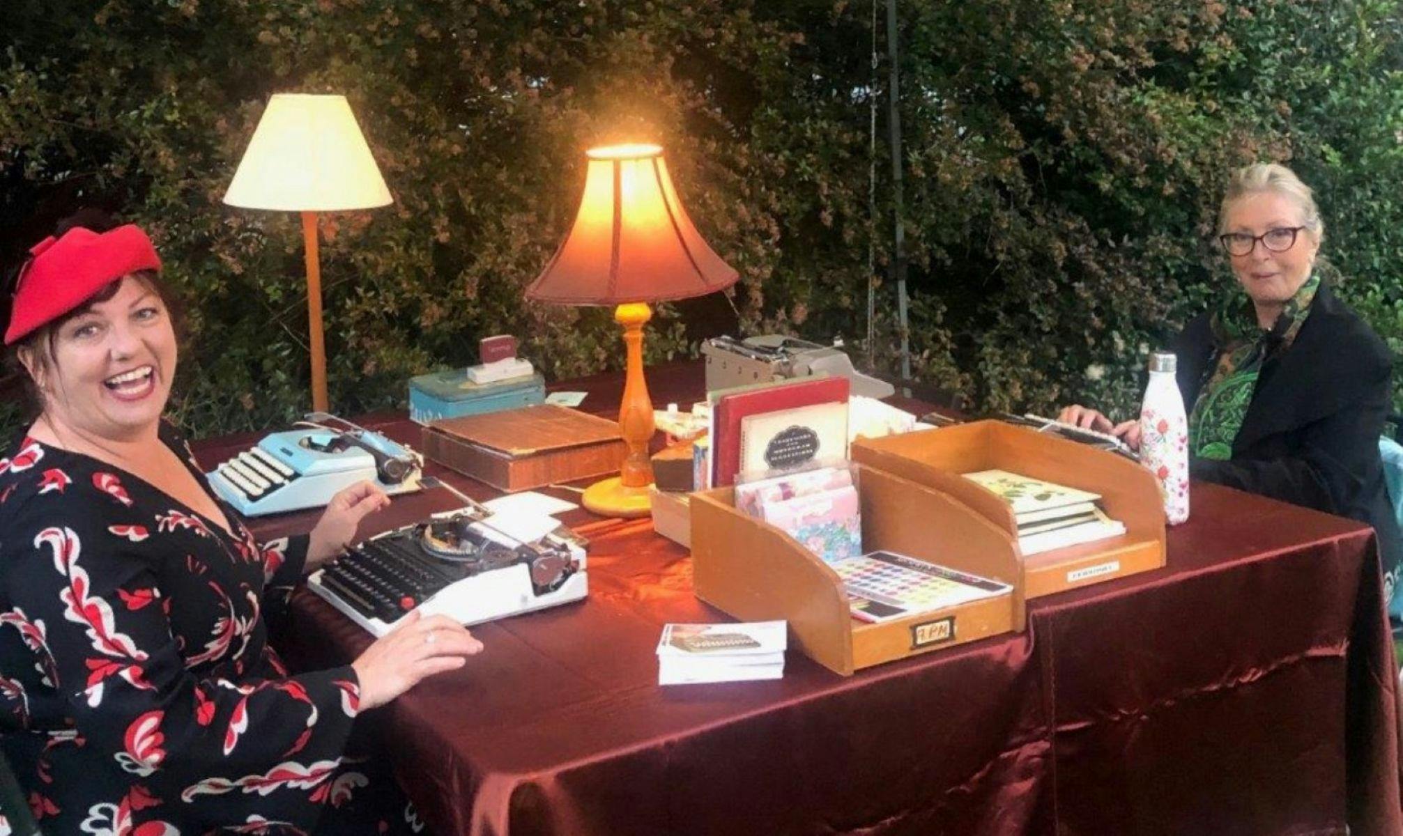 Two women sitting with typewriters and stationery