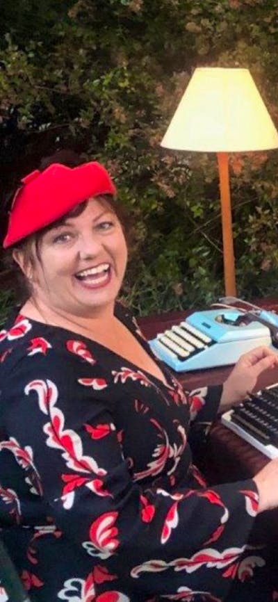 Two women sitting with typewriters and stationery
